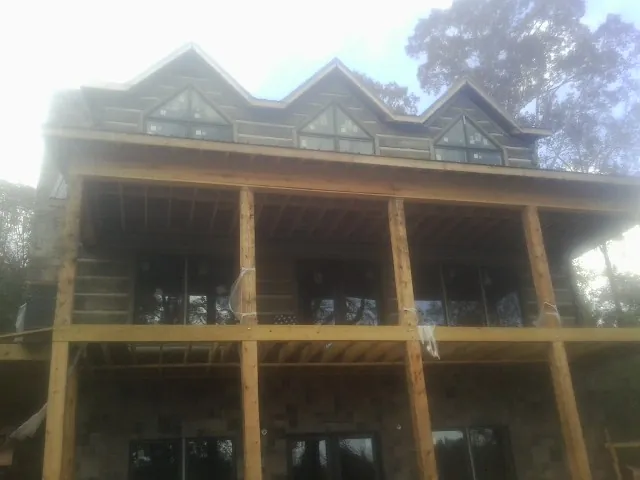 Dormers and porch framing on a large log home under construction — Roof Coating work by our crew in Mayer